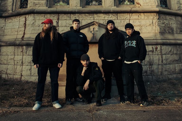 Hardcore punk band Knocked Loose posing outside a stone building with stained glass windows.